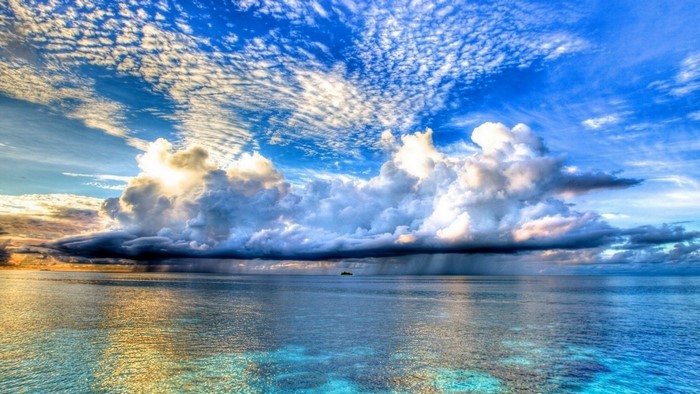 Ocean with dramatic clouds and a distant island