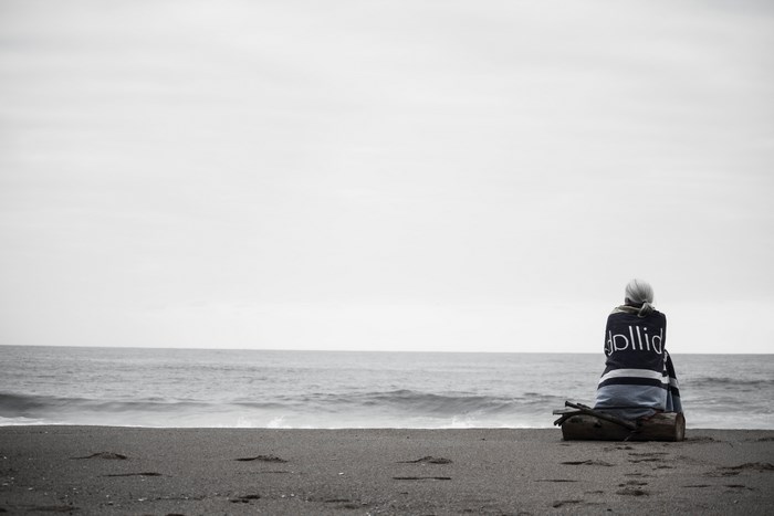 Woman sitting on a log on a beach