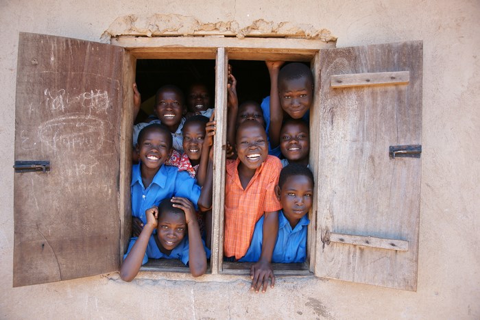 A group of happy African children peeking out of a window