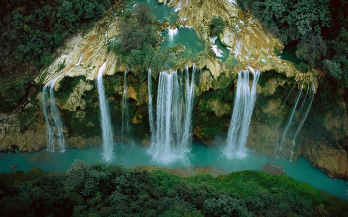 Aerial view of waterfalls cascading into a turquoise river in a lush forest in Mexico