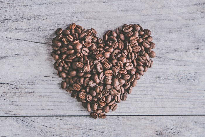 Heart shape made of coffee beans on a wooden background
