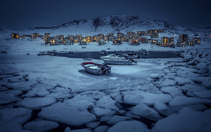 Winter village in Greenland with boats on ice