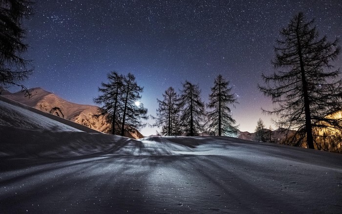 Winter night landscape with snow-covered mountains and starry sky