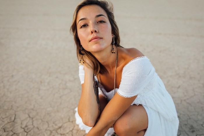 Woman in white dress crouching on cracked ground