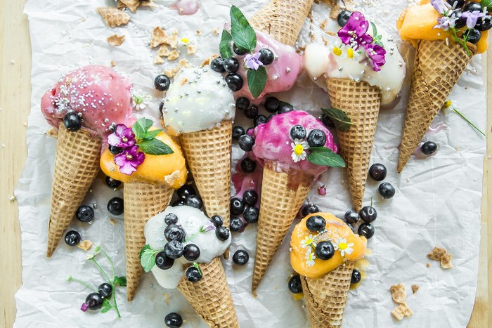 Assortment of colorful ice cream cones with blueberries and flowers