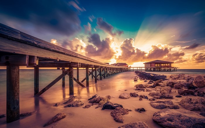 Wooden pier over the sea at sunset with sun rays