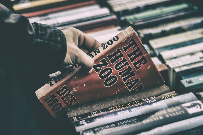Hand holding "The Human Zoo" book in a bookstore