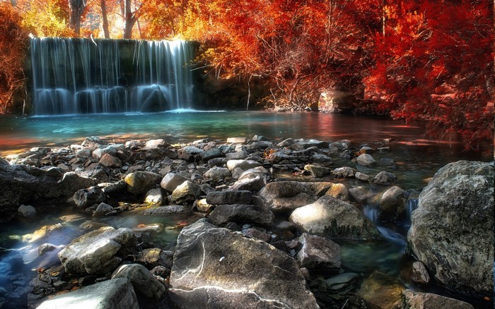 Waterfall in a rocky river with autumn trees