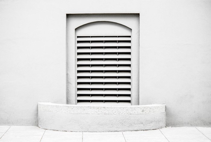 Minimalist facade with arched window and louvers