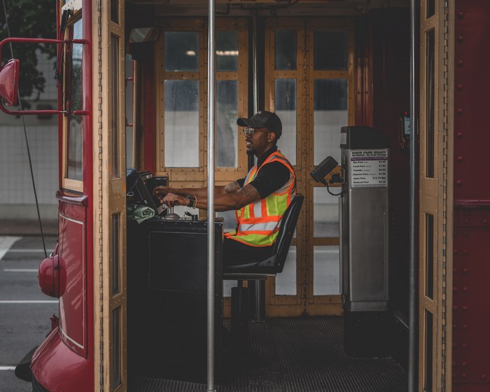 Man driving a red trolley wearing a reflective vest