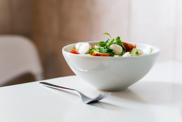 Salad with mozzarella and tomatoes in a bowl with a fork