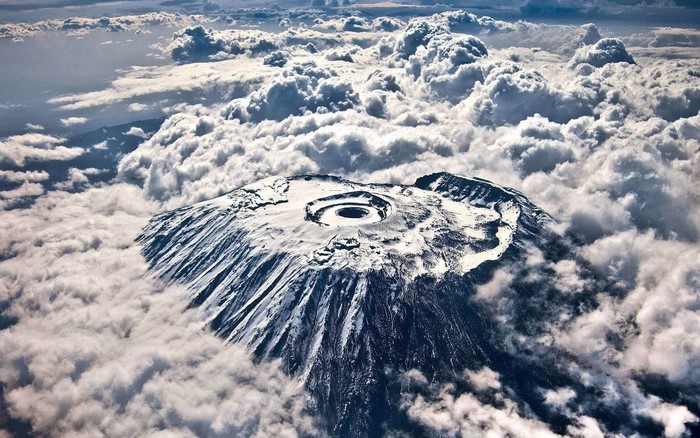 Mount Kilimanjaro peak surrounded by clouds, aerial view