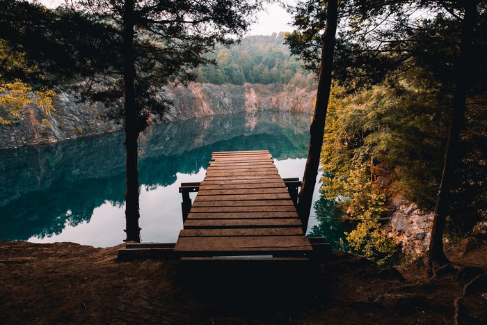 Wooden pier on a lake surrounded by trees and cliffs