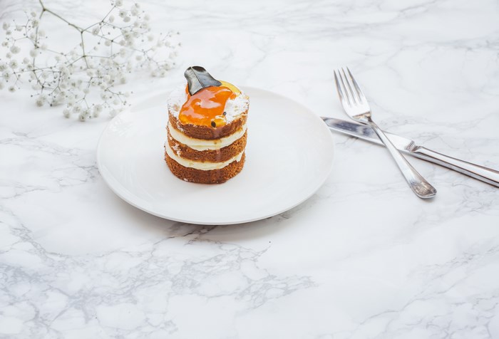 Layered Dessert Cake with Orange Topping on Marble Plate