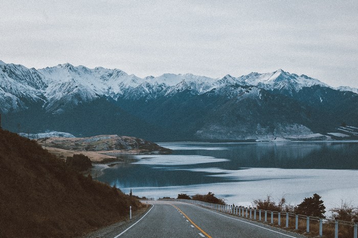 Snowy mountain range overlooking a lake and road