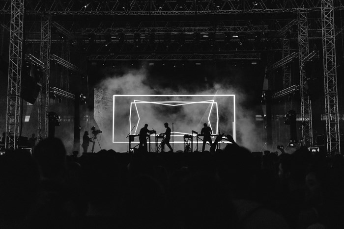 Moderat band performing on stage with neon lights