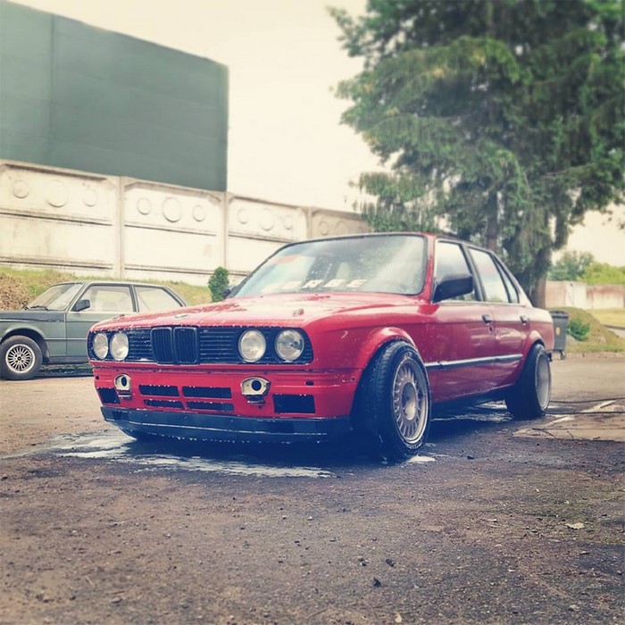 Red BMW E30 sports car parked outdoors