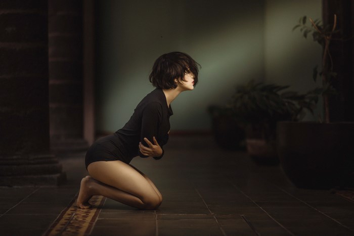 Woman kneeling in dark room with plants