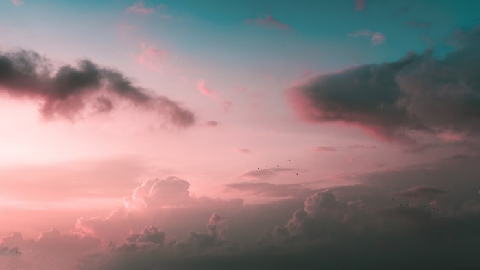 Pastel sunset sky with cumulus clouds and birds