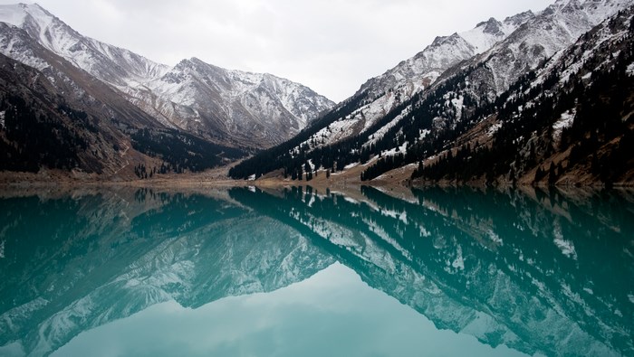 Snow-capped mountains reflected in a turquoise lake in Kazakhstan