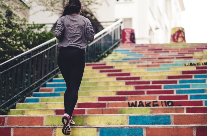 Woman running up colorful painted stairs