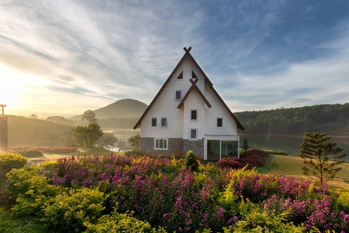 White A-frame house with flower garden by lake