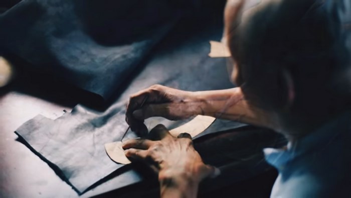Old man drawing outline on leather with a template
