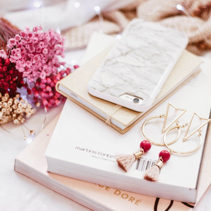 Marble phone case on books with dried flowers and earrings