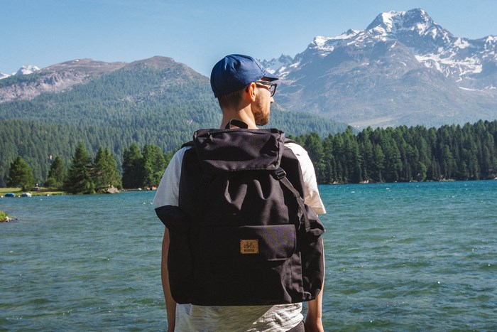 Man with backpack by a mountain lake in St. Moritz