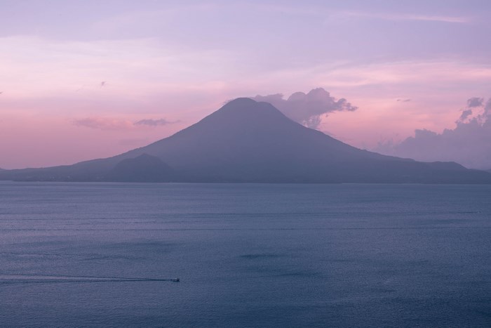 Mountain and lake at sunset with a boat