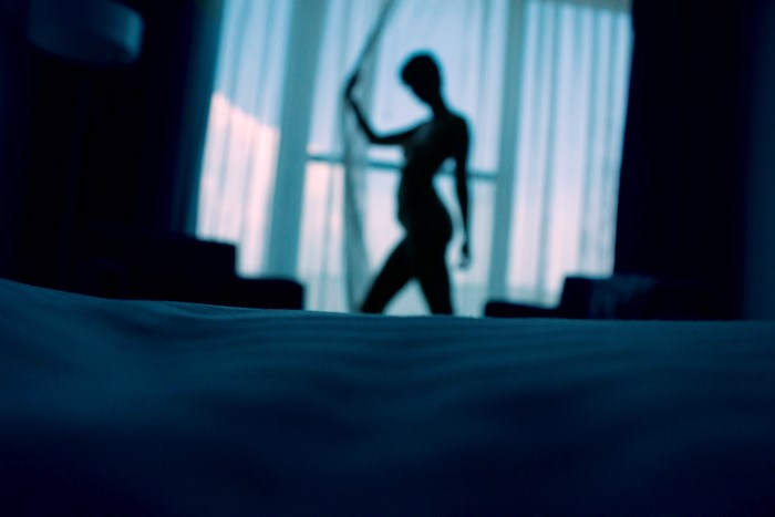 Silhouette of a woman by a window in a bedroom