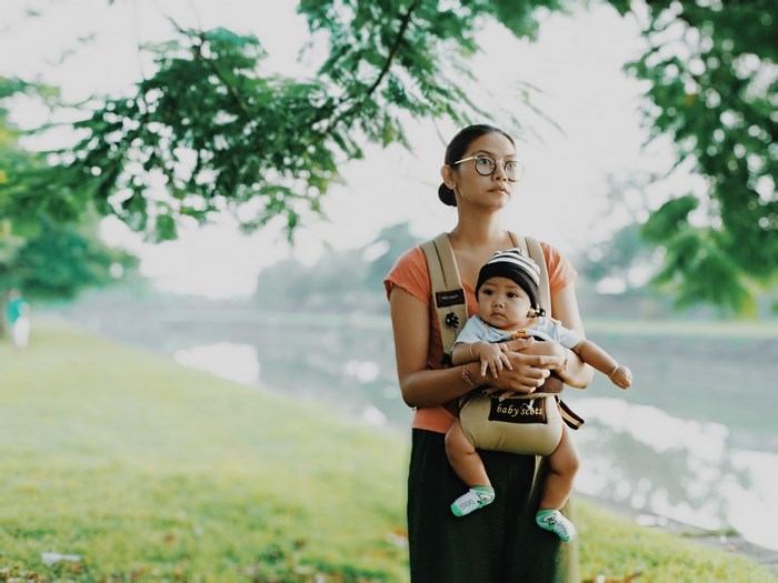 Woman carrying a baby in a carrier outdoors