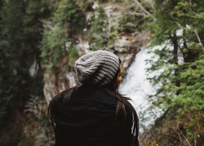 Woman in beanie looking at a waterfall