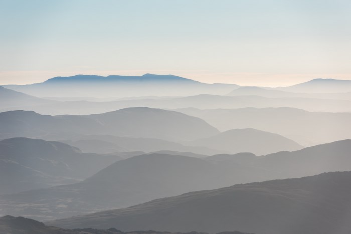 Layered mountains shrouded in mist under a clear sky