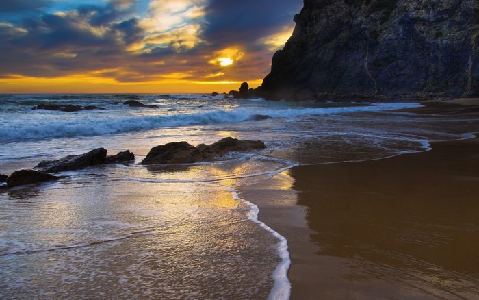 Beach cliff at sunset with waves and rocks