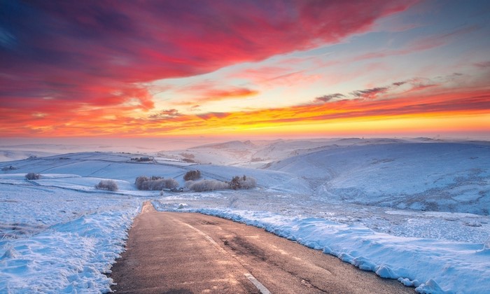 Winter road at sunset with colorful clouds