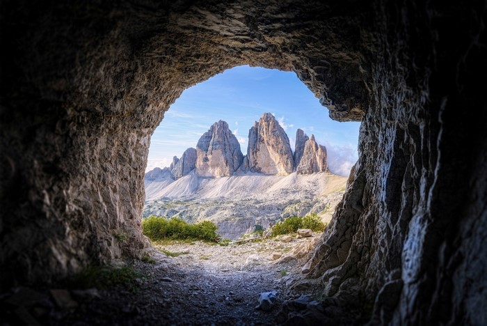 View of Tre Cime di Lavaredo mountains from a cave entrance