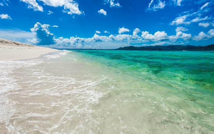 Beach with turquoise water and white sand under blue sky