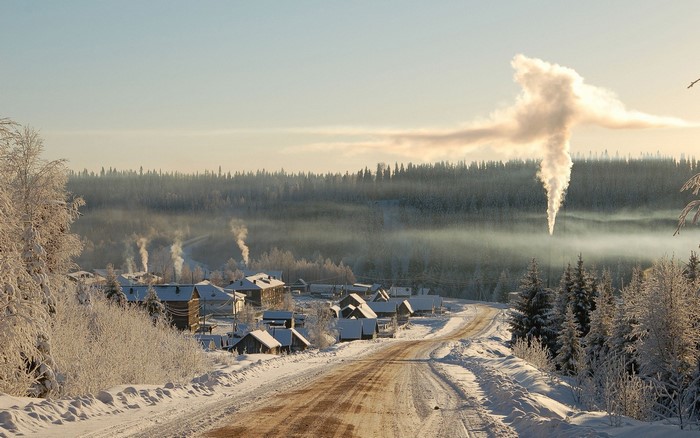 Winter village with smoke plumes in Siberia, Russia