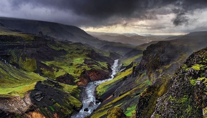 River flowing through a green canyon under stormy clouds in Iceland
