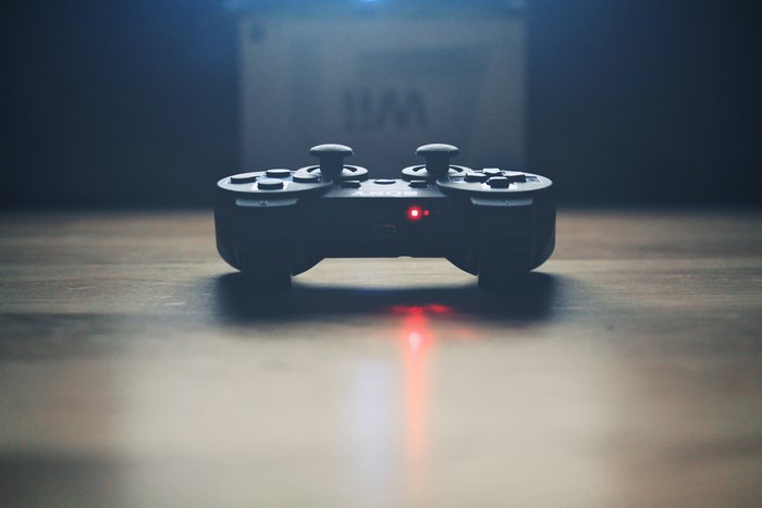 Black video game controller with red light on wooden surface