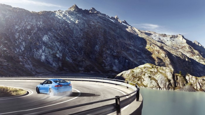 Blue Jaguar car drifting on mountain road
