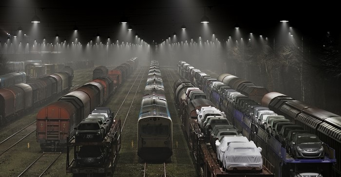 Freight trains and cars in a misty rail yard at night