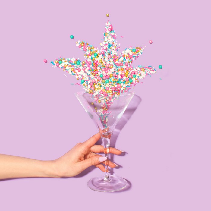 Hand holding martini glass with colorful sprinkles