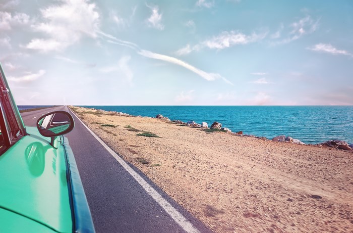 Retro car driving on a road by the sea