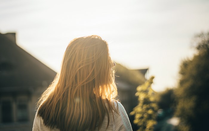 Woman with long red hair backlit by sunset