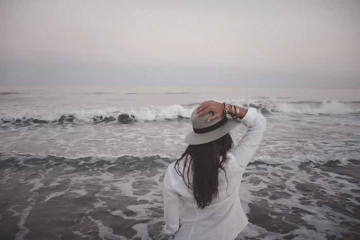 Woman in hat on beach with ocean waves