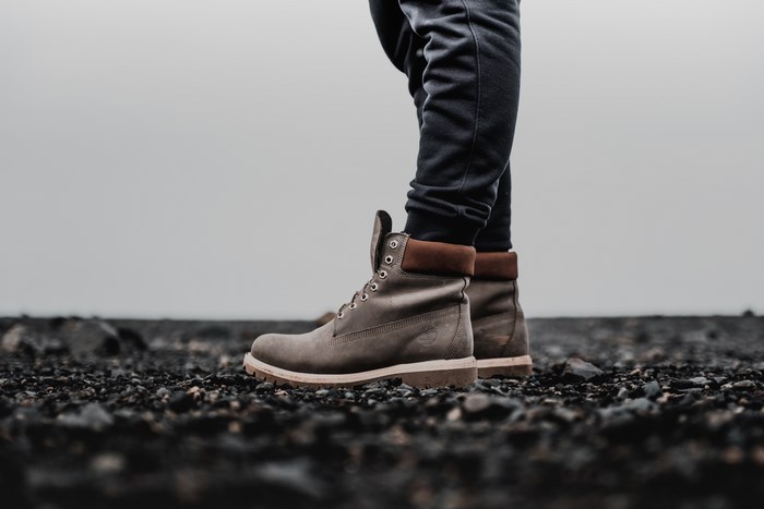 Person wearing Timberland boots on rocky ground