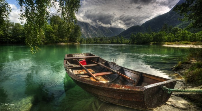 Rowboat on a clear river with mountains in the background