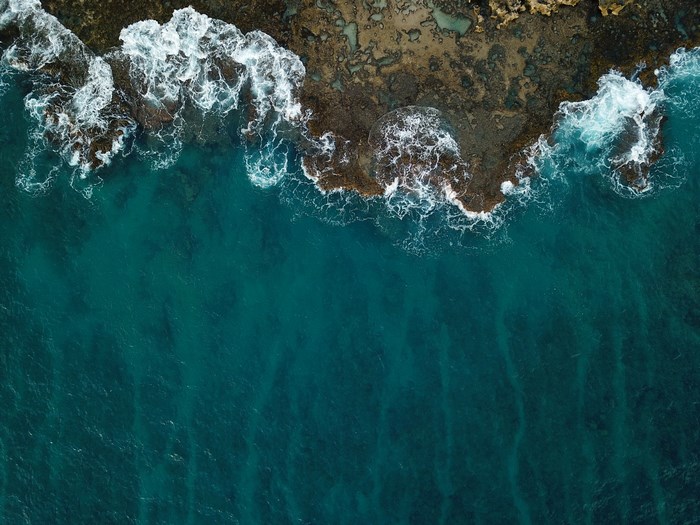 Aerial view of ocean waves crashing on a coral reef